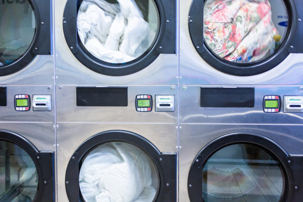Industrial Washing Machines In Multifamily Laundry Room Controlled with Laundry Mobile Apps On Smartphones