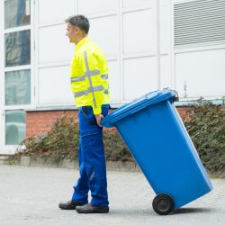 Valet Trash Worker Hauling Trash Can For A Brief Overview of Valet Trash Services Blog