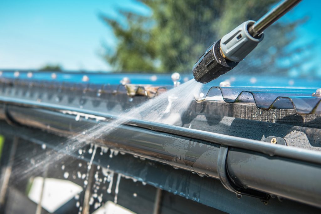 Pressure Washer Cleaning Commercial Gutters During Fall Maintenance For Commercial Properties