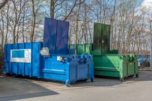 Two Trash Compactors In Parking Lot Of Aparment Building For Popularity of Valet Trash Surges Amid COVID-19 Pandemic Blog Post