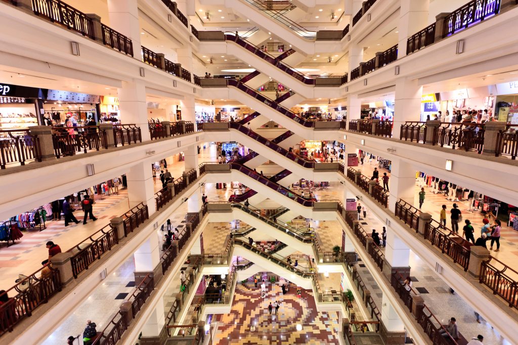 Busy Shopping Mall With Multiple Escalators And Floors