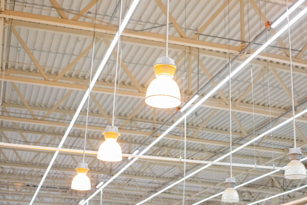 Bright LED Lamps Hanging From Industrial Warehouse Ceiling - Commercial Sustainability Projects